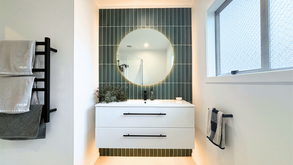 A spacious, newly renovated bathroom with modern fixtures and clean design in white and black with sage tones